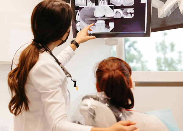 Dentist showing a dental x-ray of whole mouth dental implants to a patient on a screen in a modern clinic.